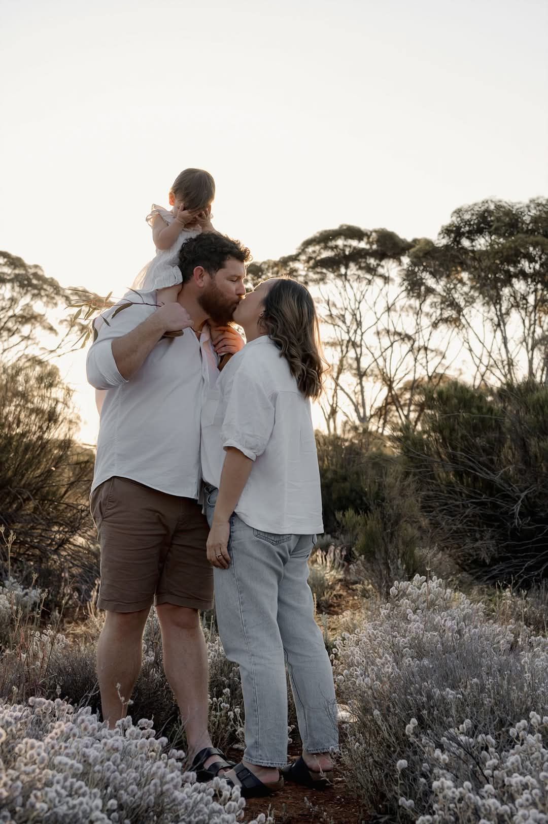 A couple shares tender moments at sunset amongst wildflowers in a natural outdoor setting - Kalgoorlie.