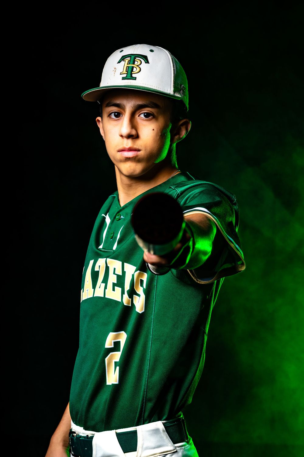 Baseball player #2 in green Blazers uniform pointing bat at camera with dramatic green smoke effect.