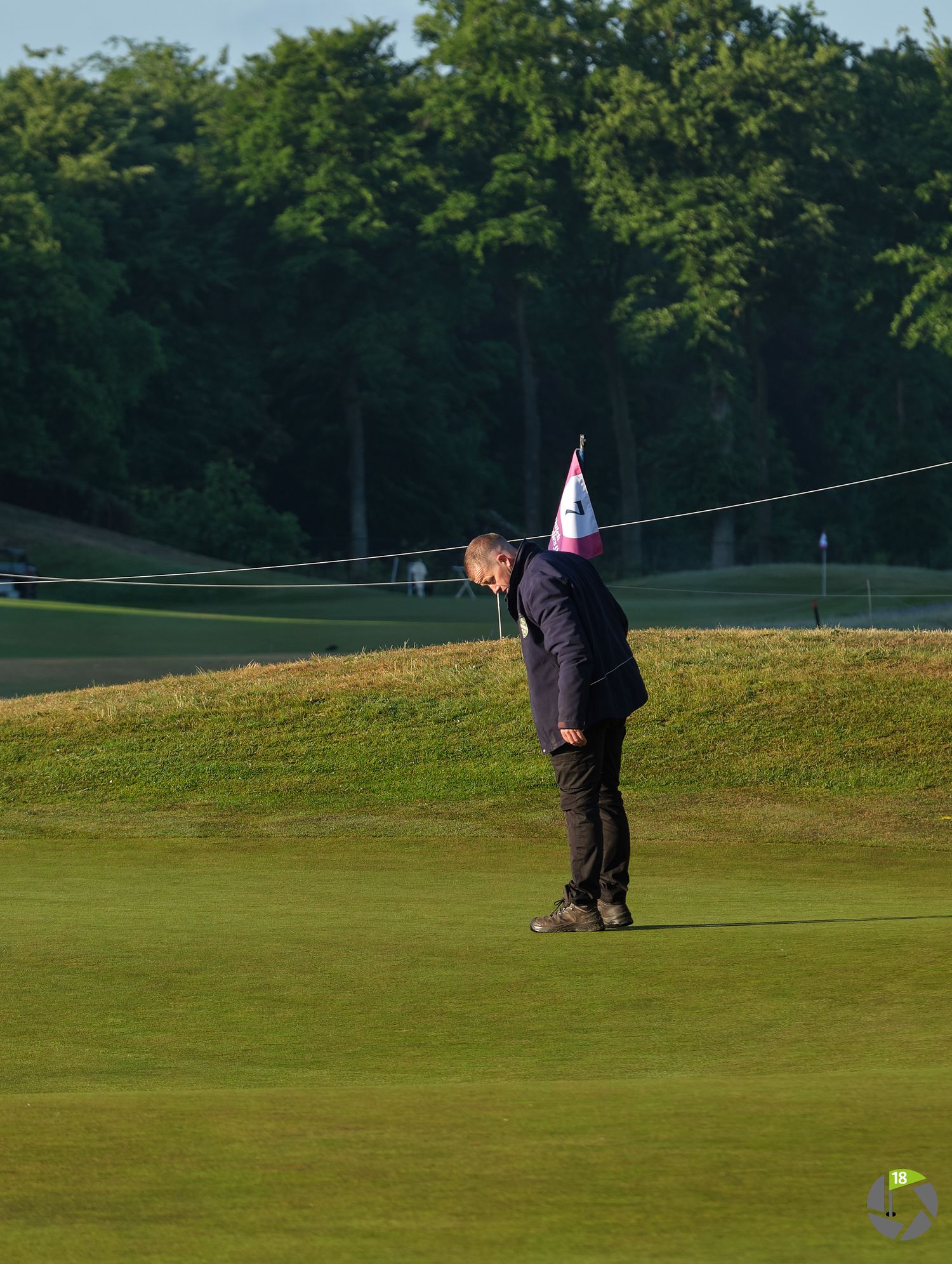Golfer putting on a manicured green during golden hour at a golf course.