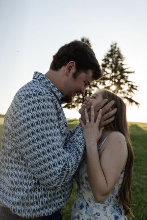 A romantic sunset photo of a couple holding each other's faces tenderly.