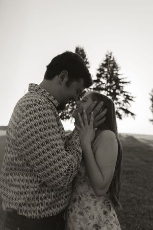 A black and white portrait of a couple sharing an intimate moment outdoors.