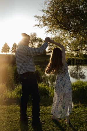 Silhouetted couple standing together in golden evening light by a lake.