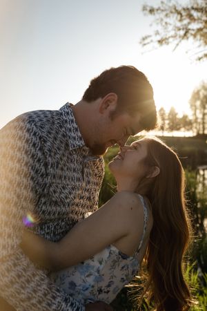 Golden sunlight illuminates romantic couple during outdoor photoshoot.