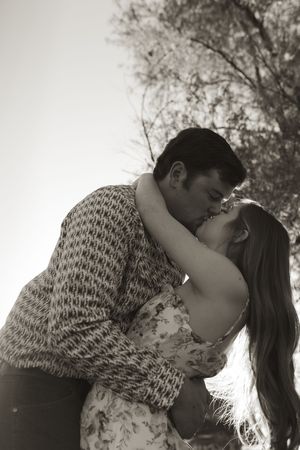 Black and white portrait of couple in intimate embrace outdoors.