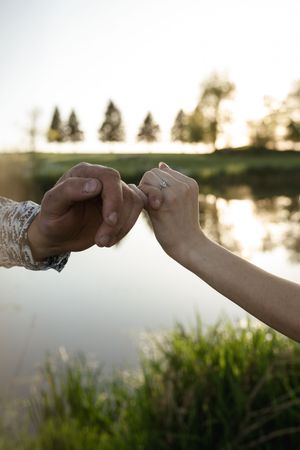 Engagement ring exchange captured against a serene lake backdrop at golden hour.