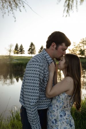 Romantic couple sharing a tender moment by a lake during sunset.