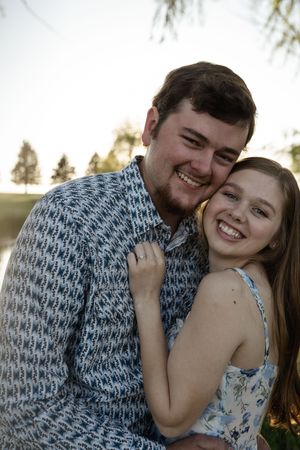 Joyful couple sharing laughter during their lakeside engagement photoshoot.