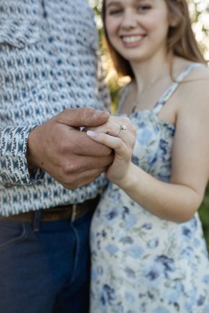 Close-up shots of hands exchanging rings during an outdoor engagement photoshoot.