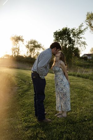 A couple shares romantic moments in a sunlit field during golden hour.