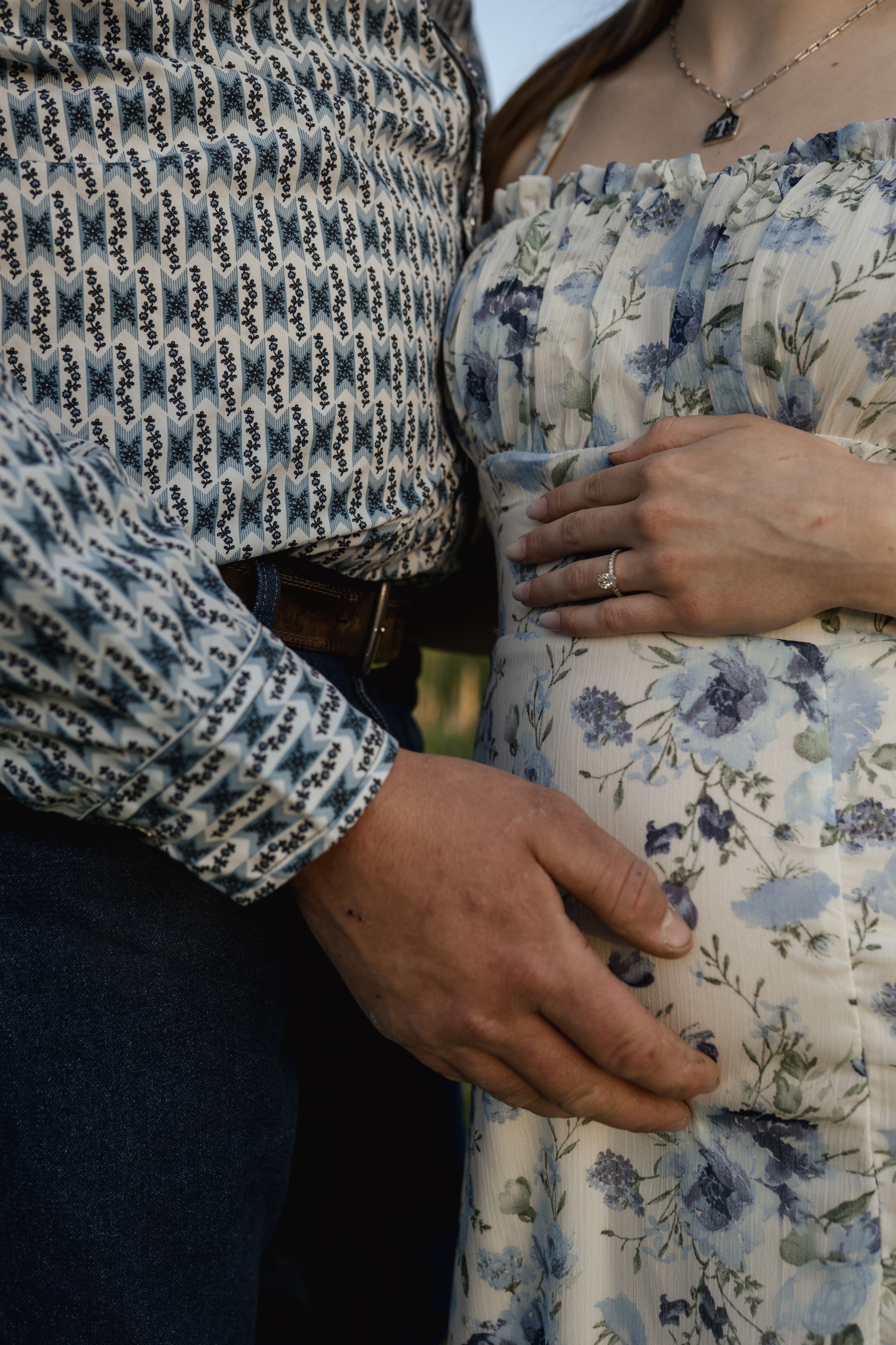 Close-up of couple in floral and patterned clothing embracing outdoors.