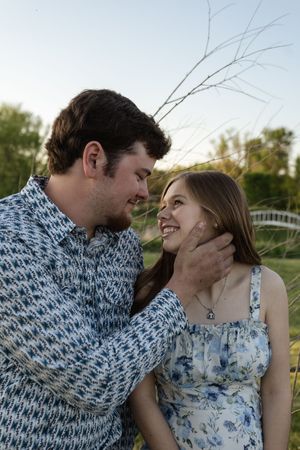 Two people in coordinating blue and white outfits share an intimate moment outdoors.