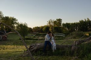 Rural landscape at golden hour with couple standing near wooden fence.