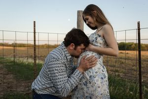 Intimate outdoor portrait against rural sunset landscape.