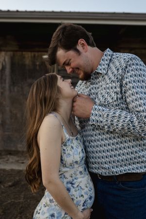 A romantic moment captured between a couple in a floral dress and knit sweater outdoors.
