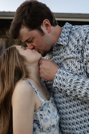 An intimate moment between a couple wearing a patterned sweater and floral dress.