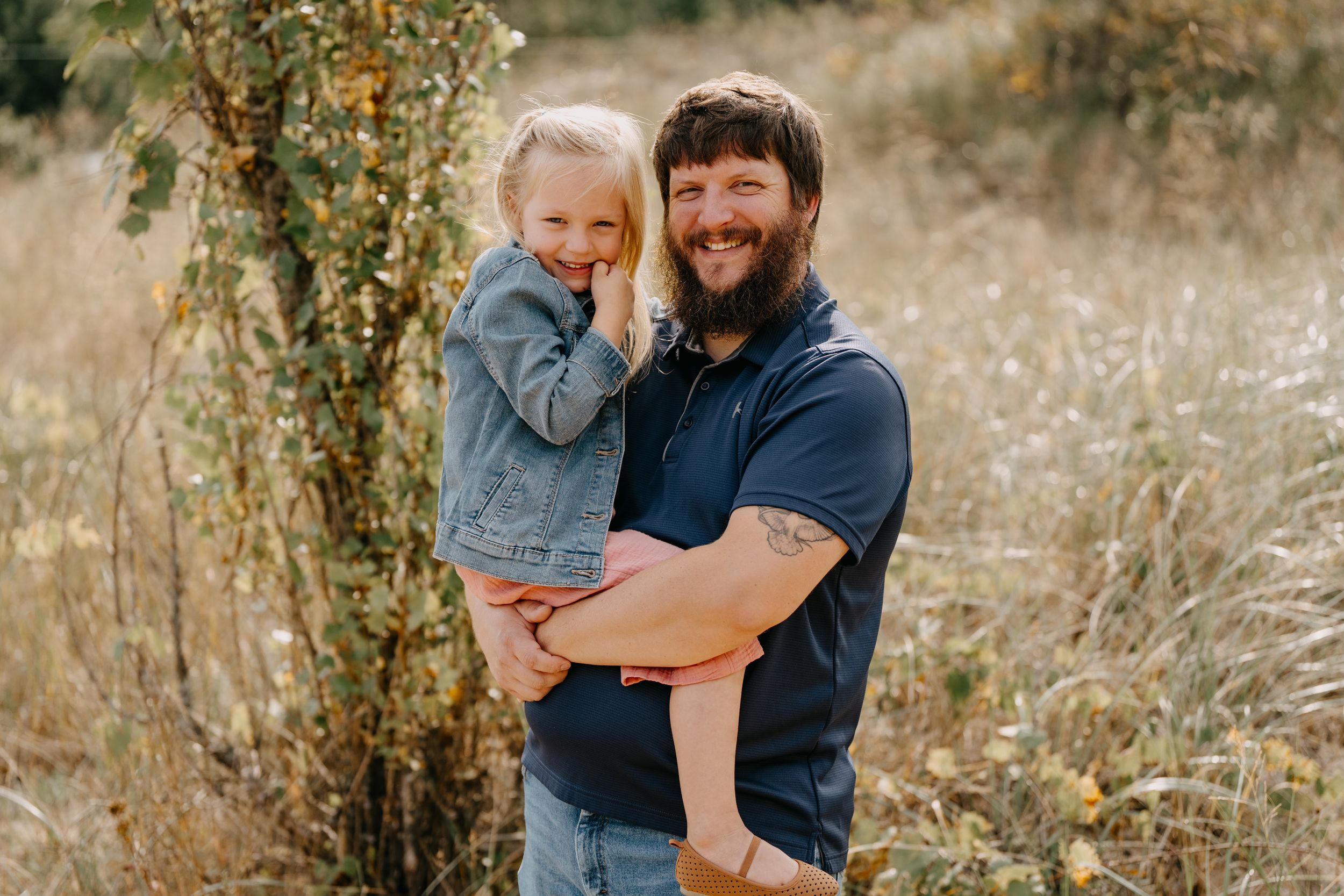 Two people share a joyful outdoor moment together in a rustic field with tall grass and greenery.