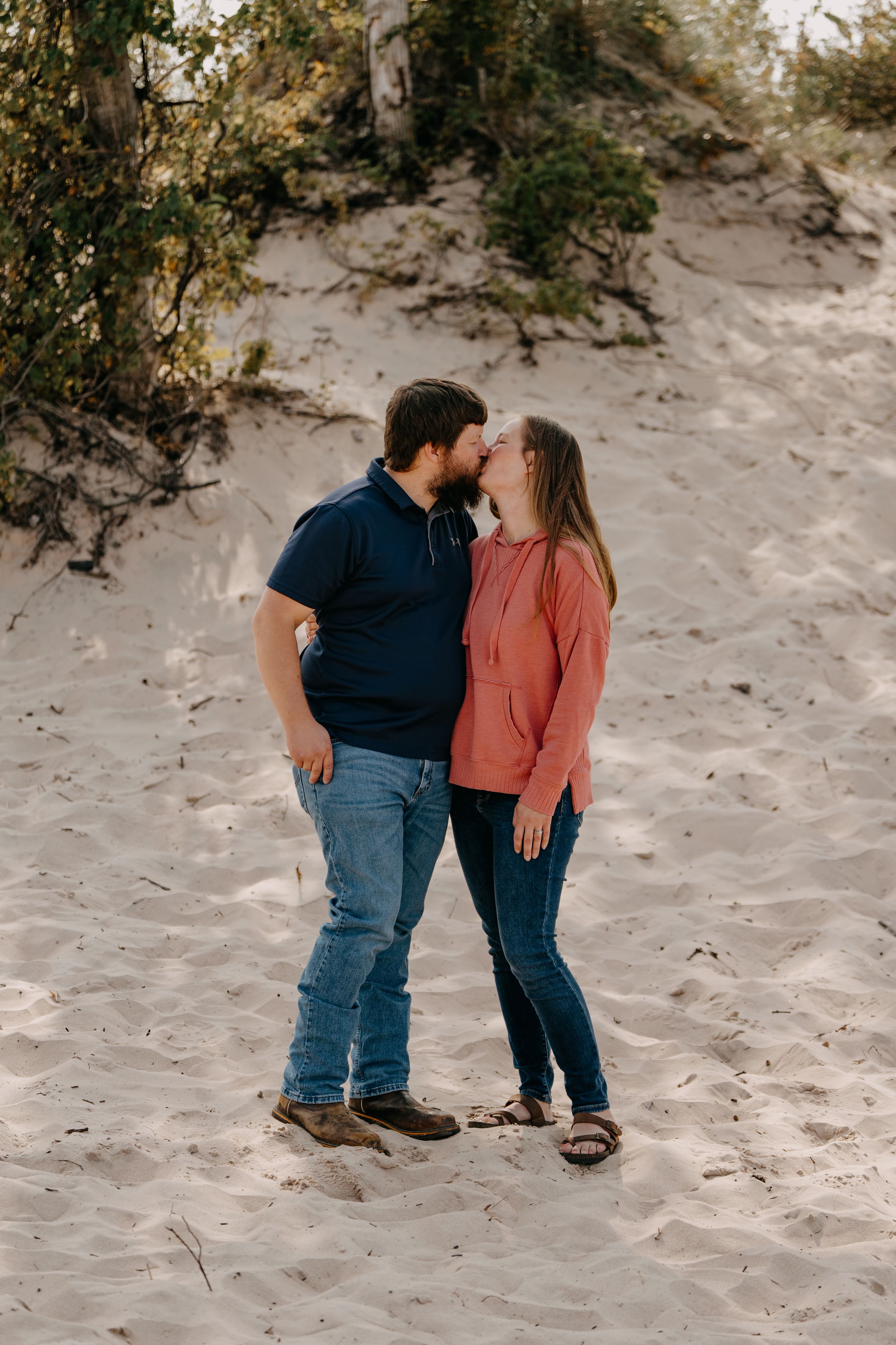 Couple sharing romantic moment together while standing on sandy beach terrain.