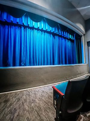 A stage or dance studio with blue curtains and wooden flooring shown from multiple angles during setup.
