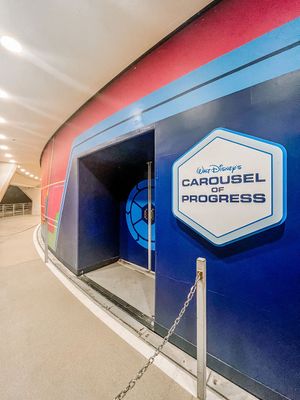 Sign for Walt Disney's Carousel of Progress attraction entrance with curved blue and red wall design.