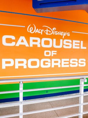 Vintage orange sign for Walt Disney's Carousel of Progress attraction with blue and green stripes along the bottom.