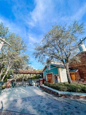A rustic retail area with wooden walkways and buildings under blue skies at an outdoor shopping district.