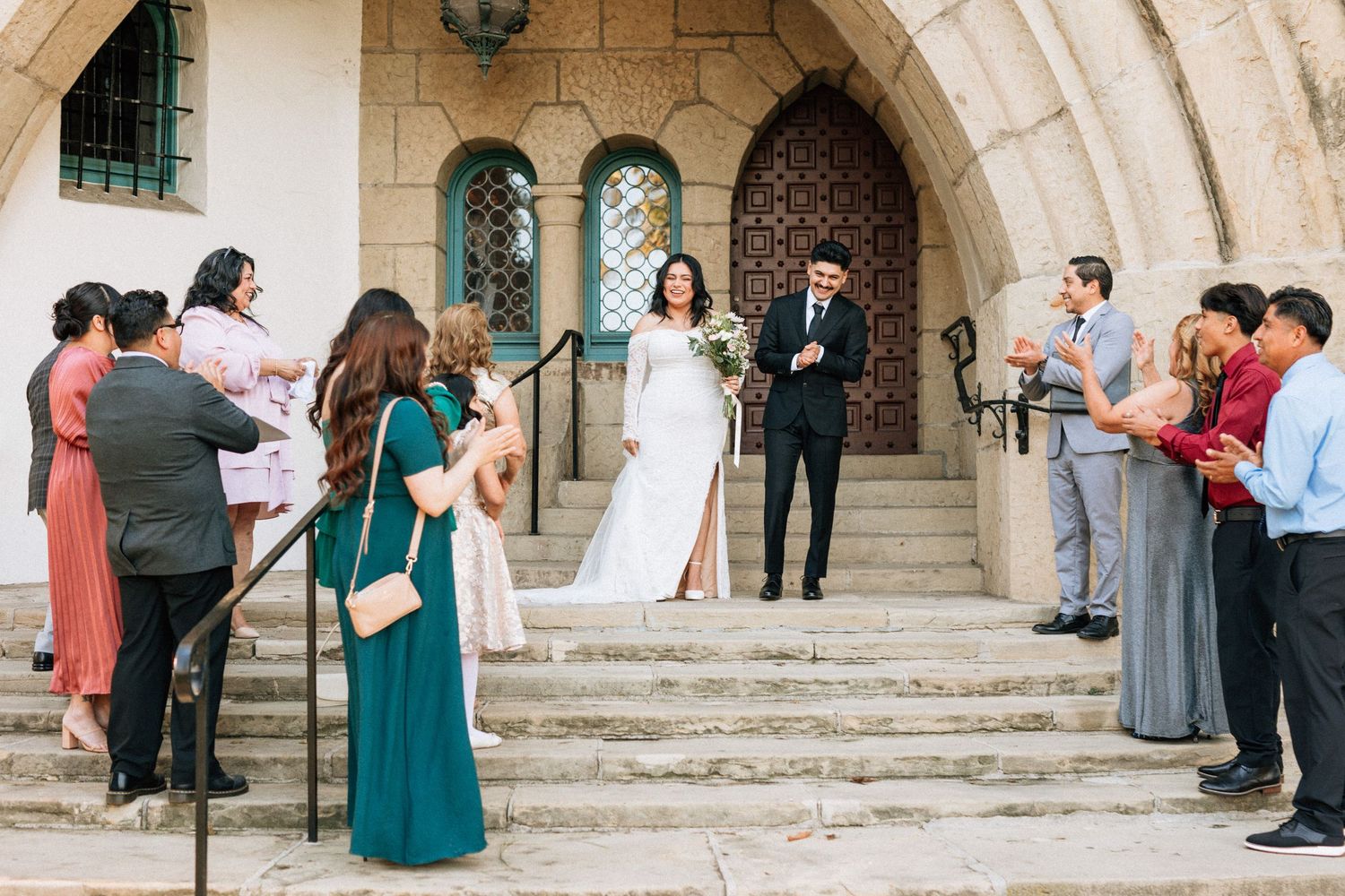Wedding ceremony guests gather on stone church steps to celebrate a couple's special moment in formal attire at the Santa Barbara Courthouse