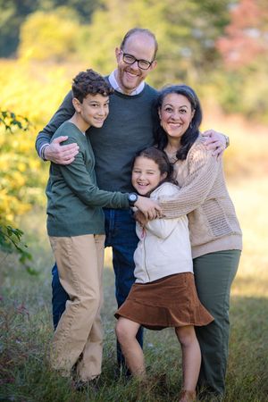 A family shares joyful moments together outdoors during an autumn photo session in a natural setting.