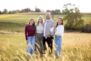 A group enjoys a candid moment together while walking through a golden autumn wheat field at sunset.