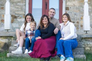 A family group sits together on stone church steps outdoors on a sunny day.