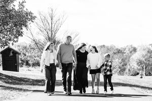 A group of people walk together on a path in black and white, creating a casual outdoor family portrait.