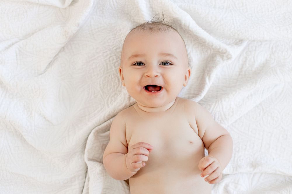 Baby smiling on white blanket in a lifestyle session in Springfield Missouri.
