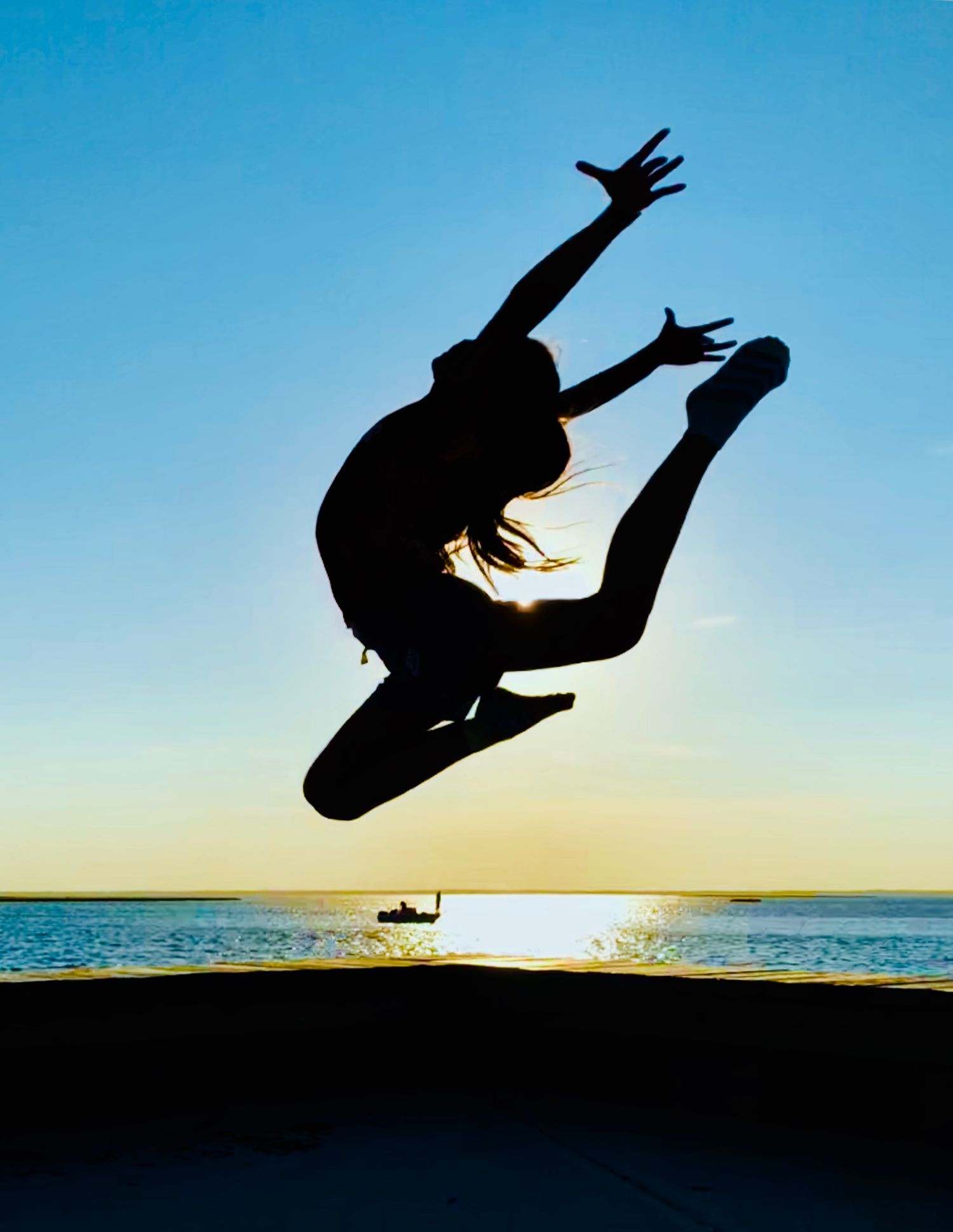 Silhouette sequence of gymnast performing aerial moves against sunset sky and ocean backdrop.