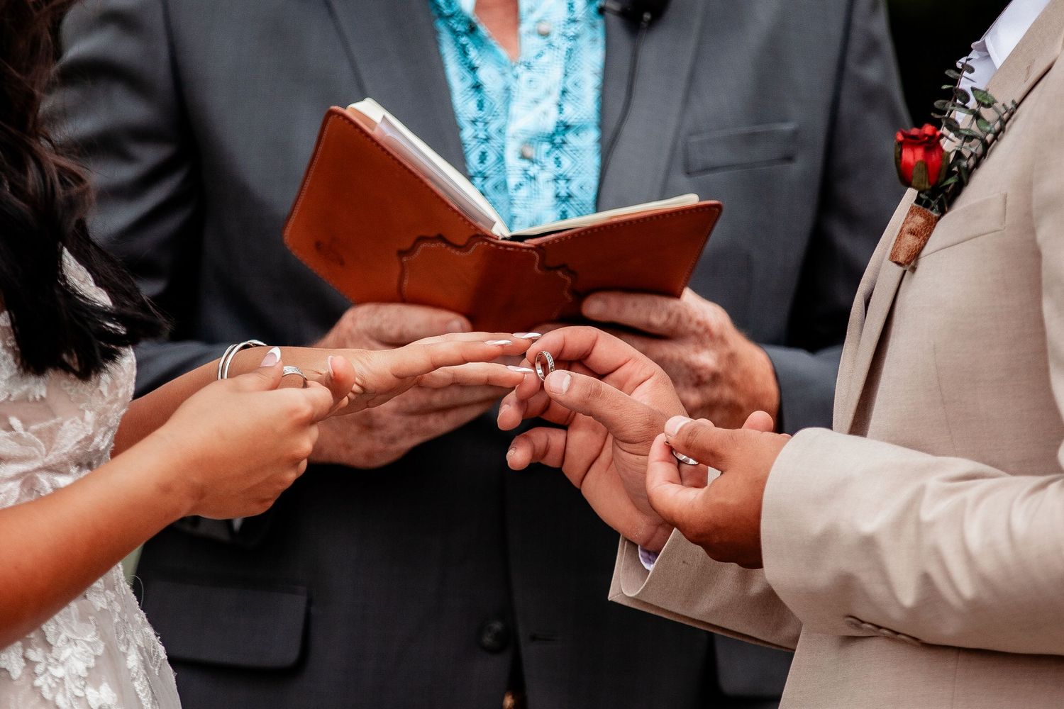 Close-up of hands exchanging wedding rings during ceremony.
