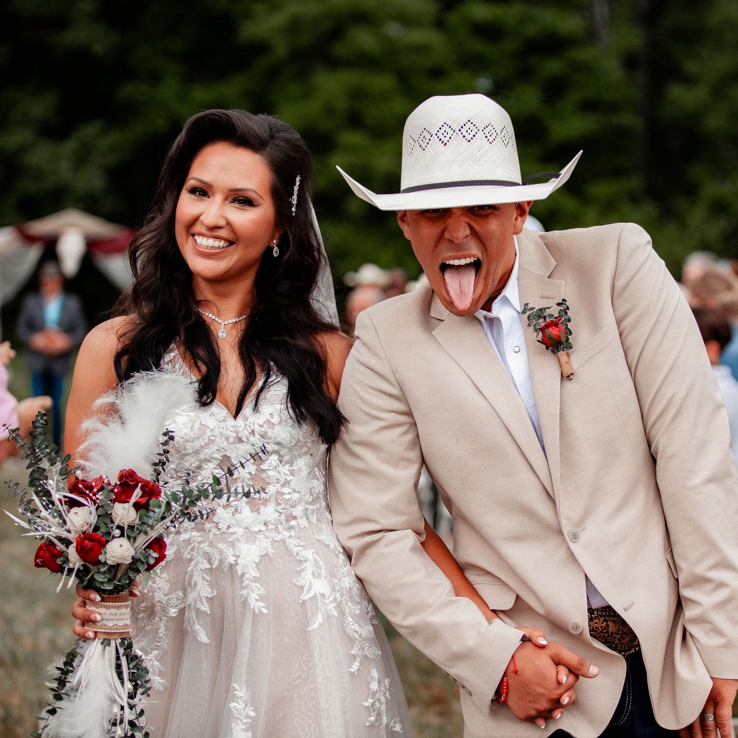 Playful wedding moment captured under rustic outdoor decor with cowboy theme.