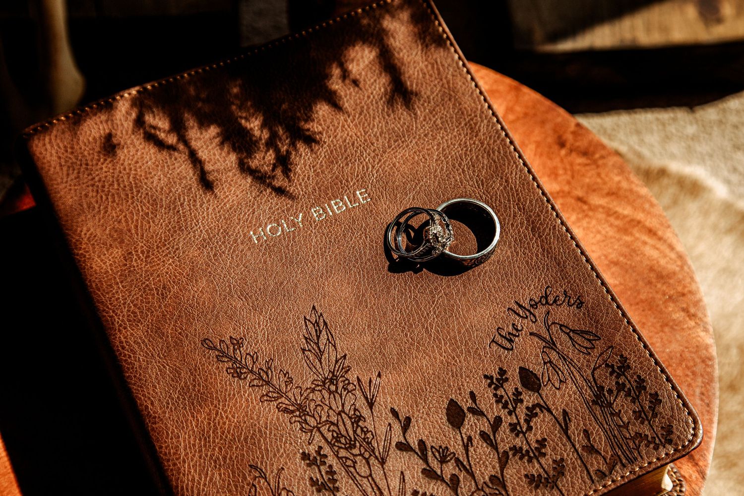 A brown leather journal with floral engravings and a wedding ring resting on its surface.