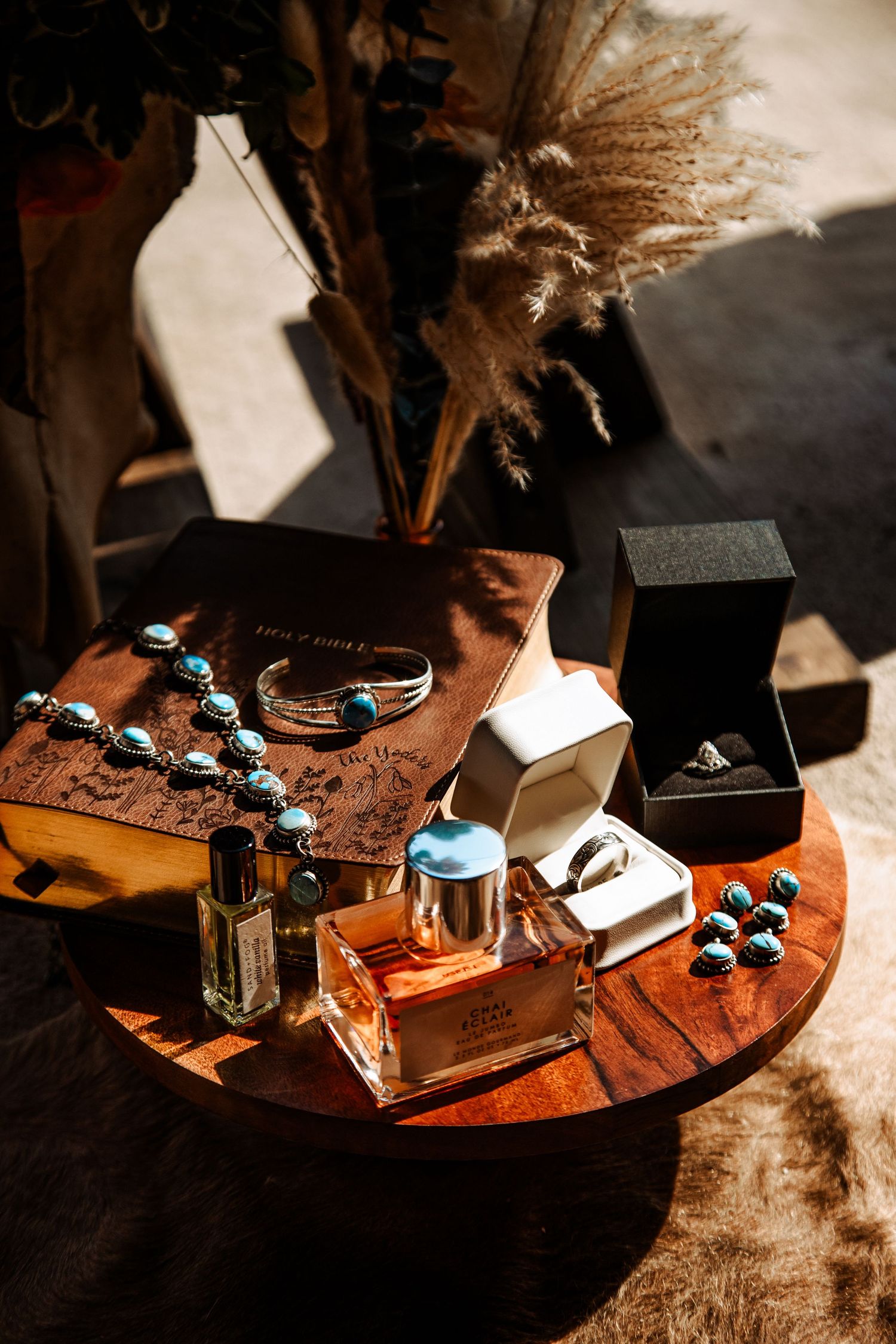 Artistically arranged turquoise and silver jewelry pieces displayed on a rustic wooden surface in warm lighting.