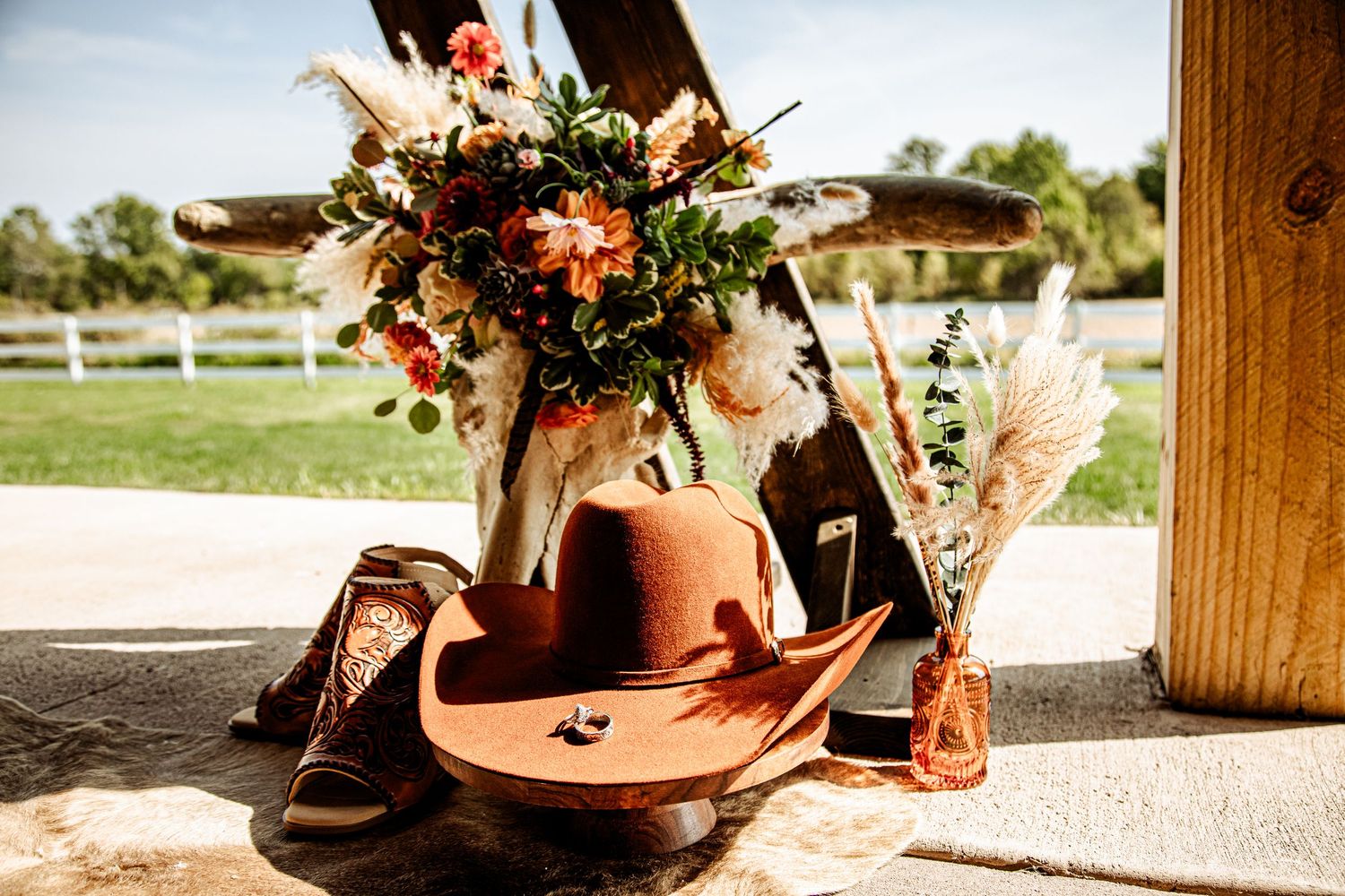 A rustic arrangement of dried flowers and boots displayed on a wooden surface in natural sunlight.