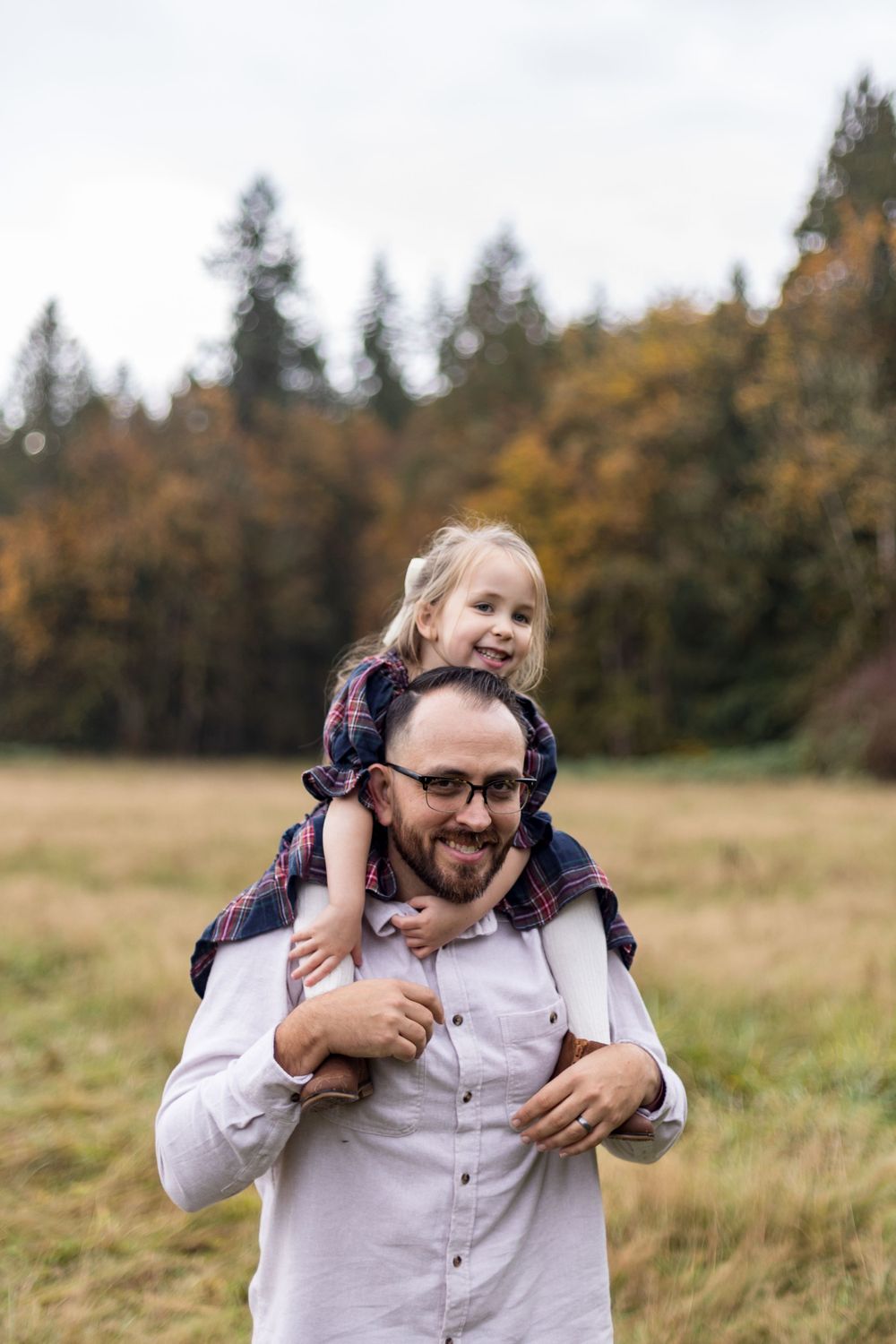 A joyful moment in an autumn field with tall evergreen trees in the background.