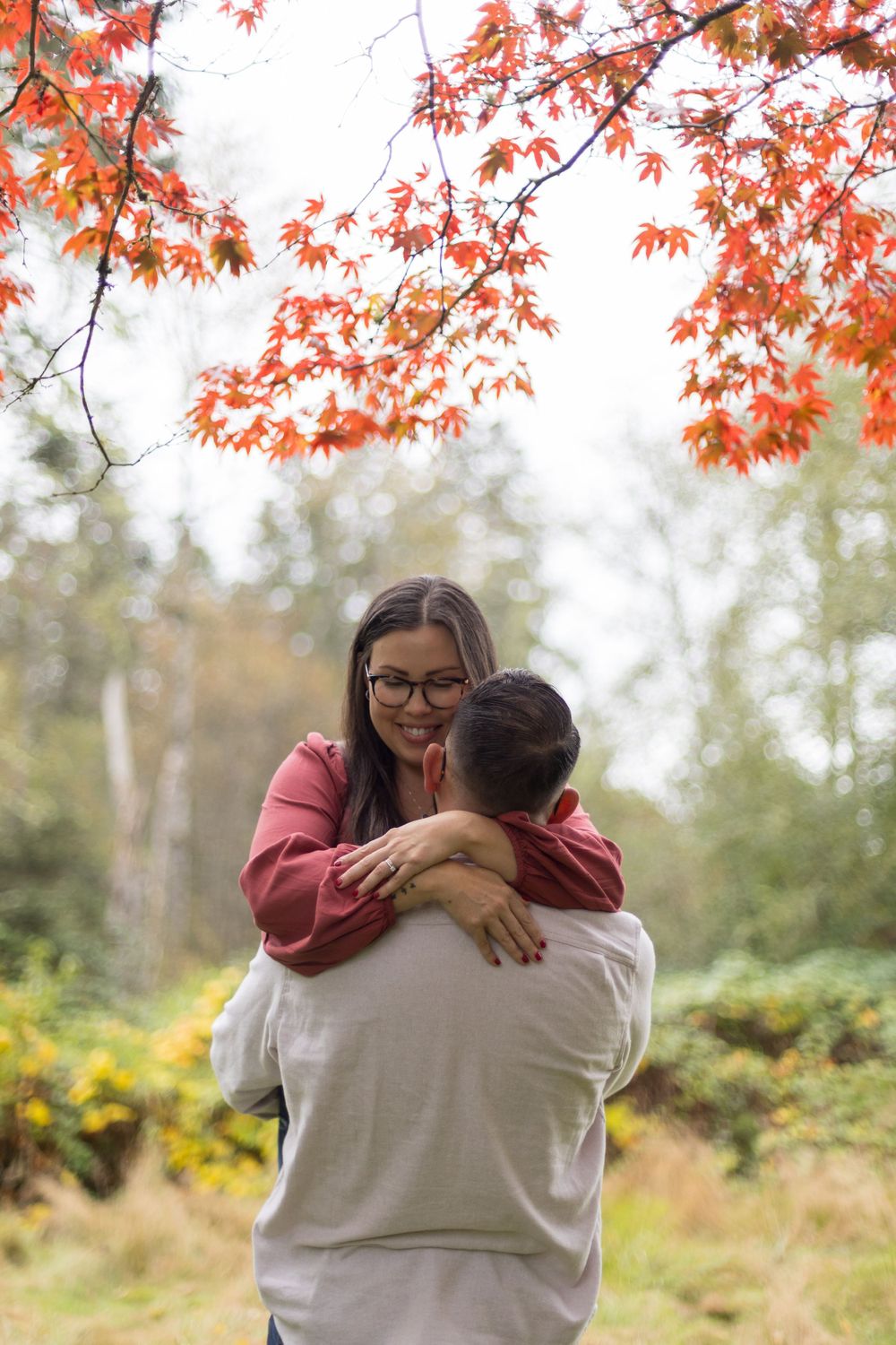 A romantic fall scene with autumn maple leaves overhead as a couple embraces beneath the colorful canopy.