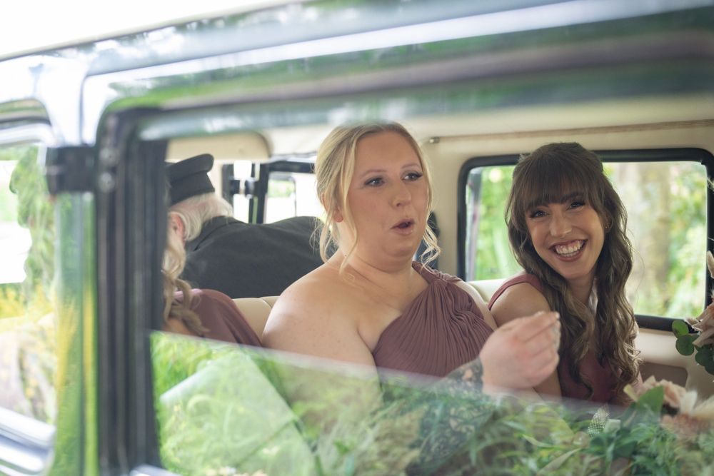 Wedding guests enjoy a candid moment inside a vintage vehicle.