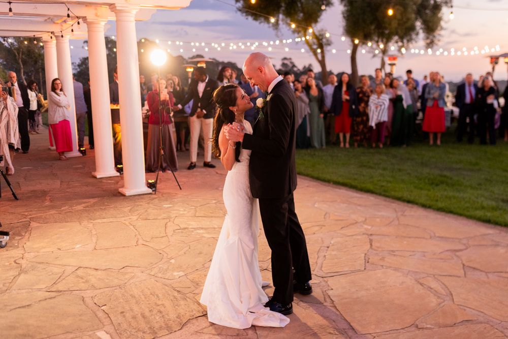 Romantic evening dance moment on a stone patio under string lights.