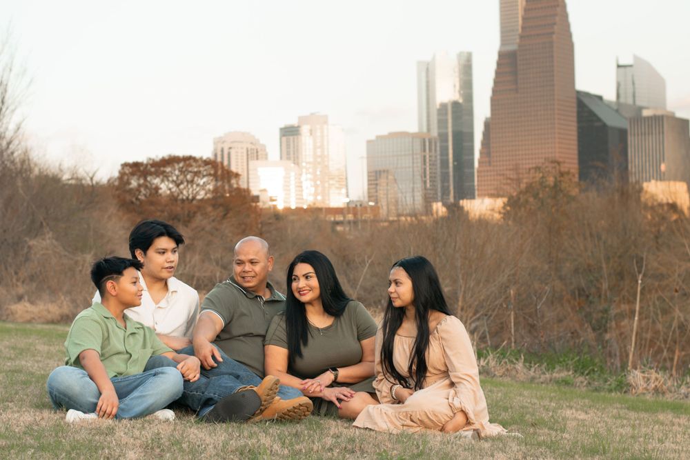 Family gathering sitting on grass with Houston downtown skyline in background.