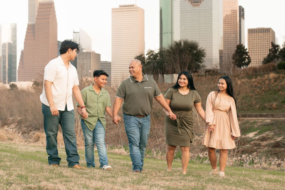 Family walking together on a grassy hill with Houston's downtown skyline in the background.
