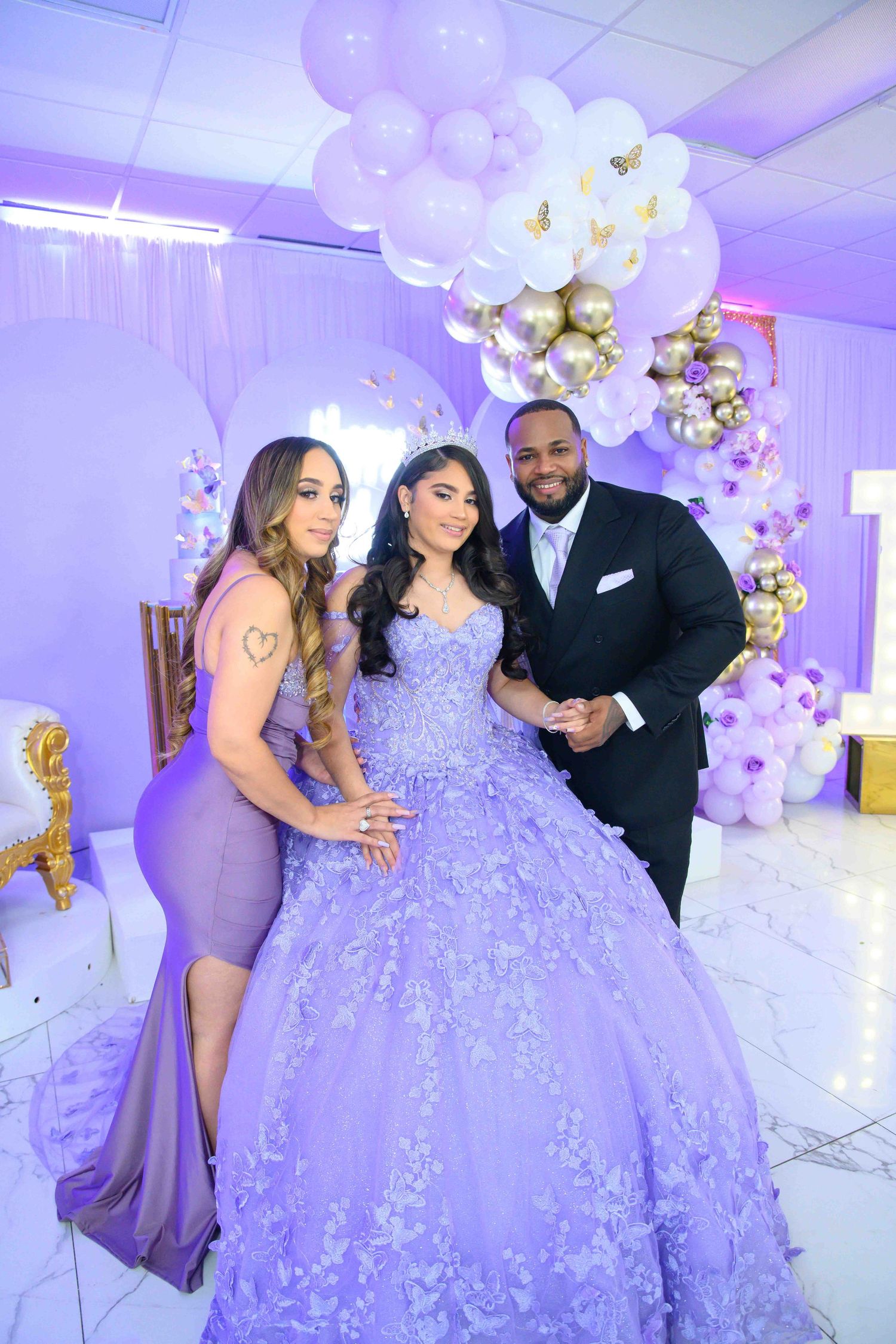 Elegant celebration with balloon arch decorations in purple and white with formal attire in a lavishly decorated room.