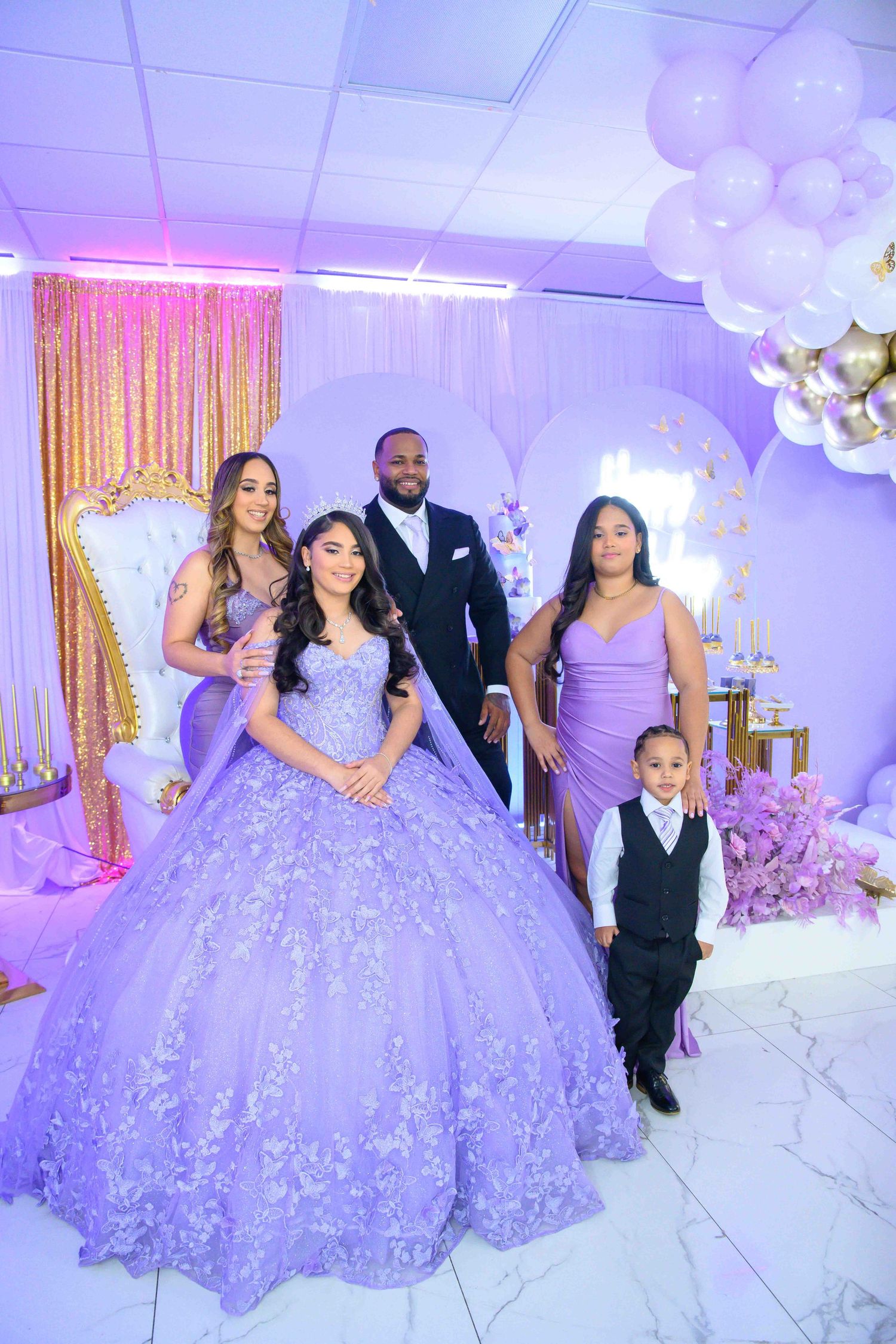 A quinceañera celebration features a lavender ball gown and elegant purple and gold party decorations.