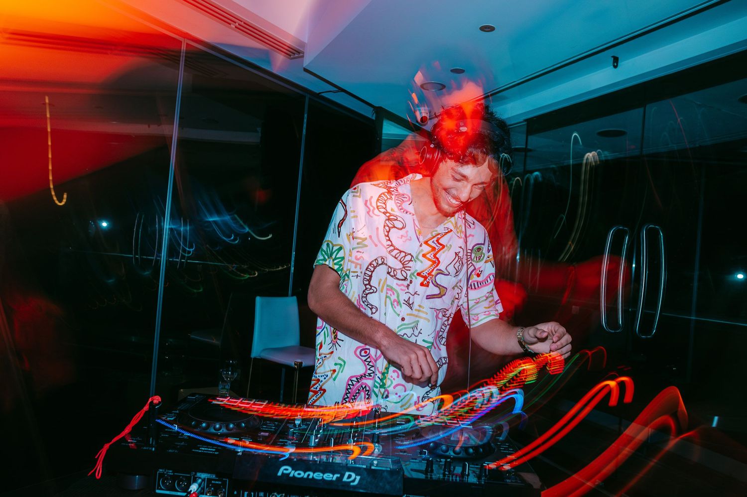 DJ performs at nightclub under dramatic red and blue lighting effects.