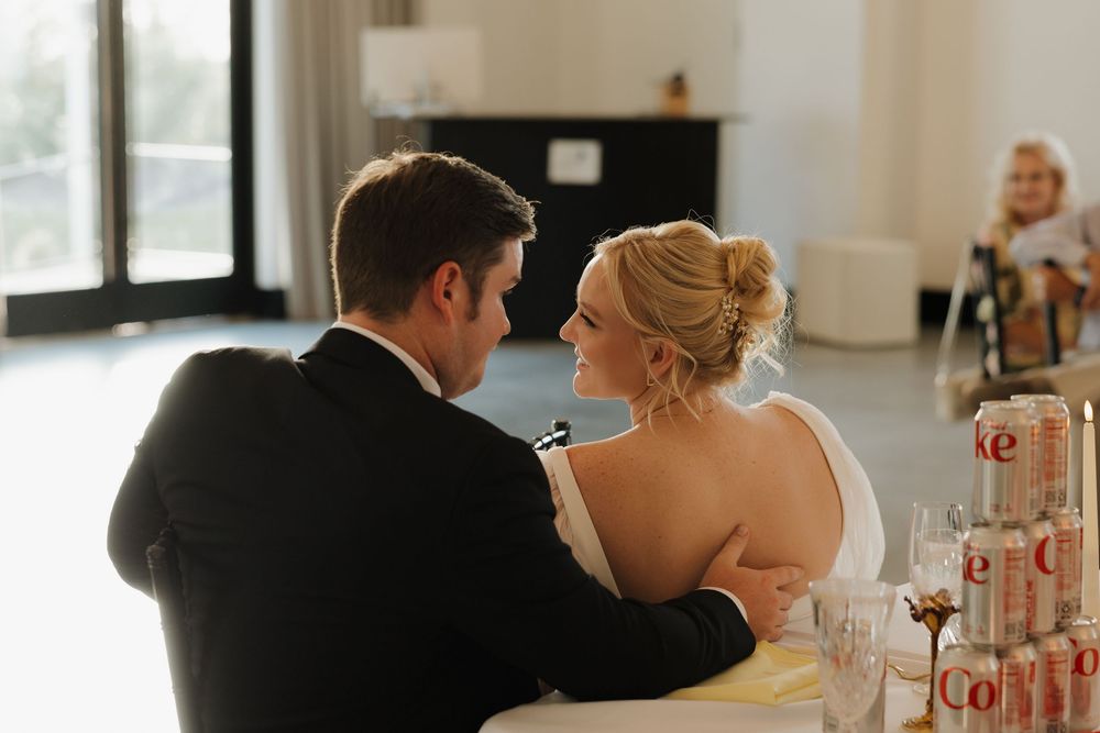 A romantic wedding reception moment captured with guests raising champagne glasses in a toast during dinner.