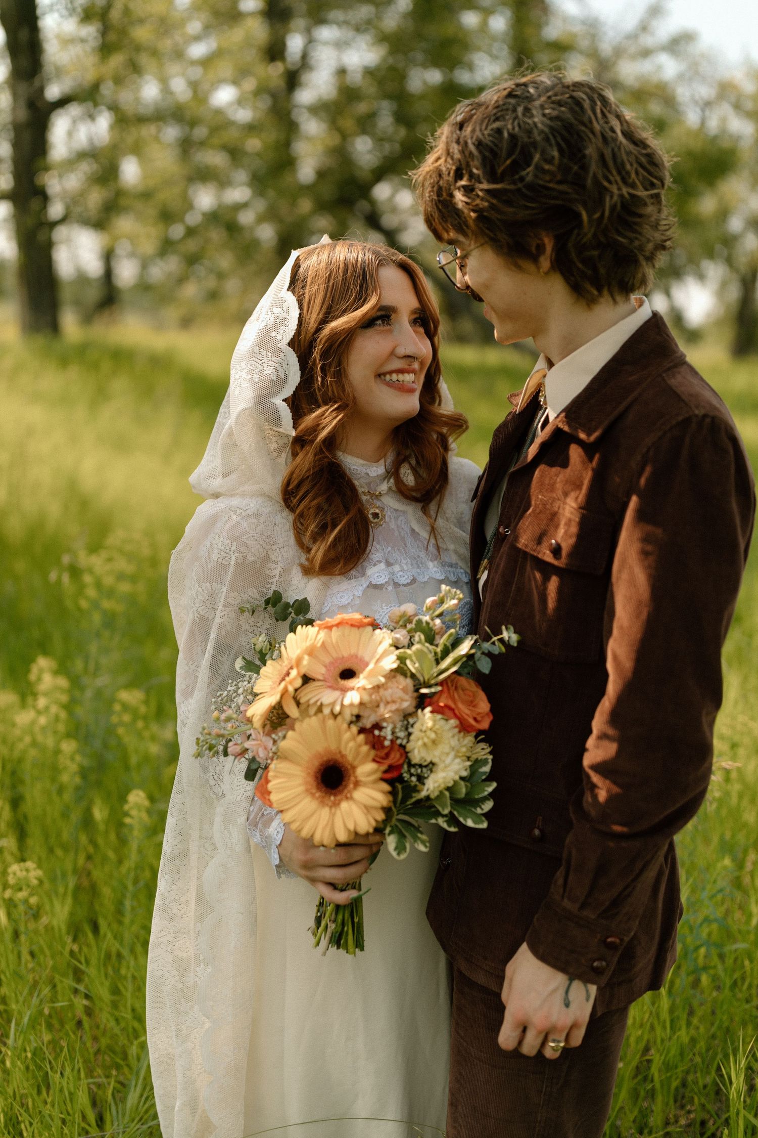 Wedding couple with sunflower bouquet in rustic outdoor setting.