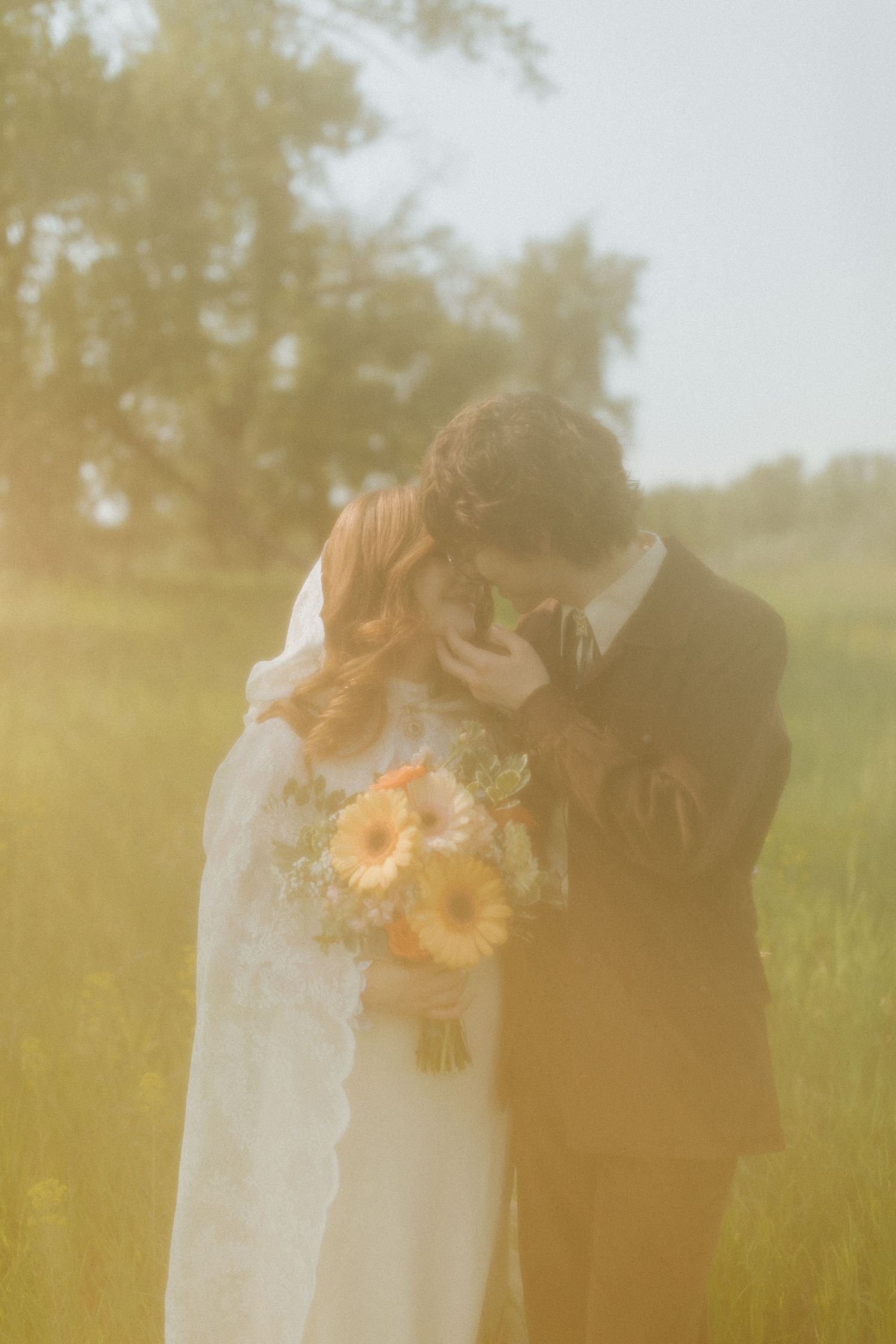Dreamy golden hour wedding portrait in a sunlit meadow with wildflowers.