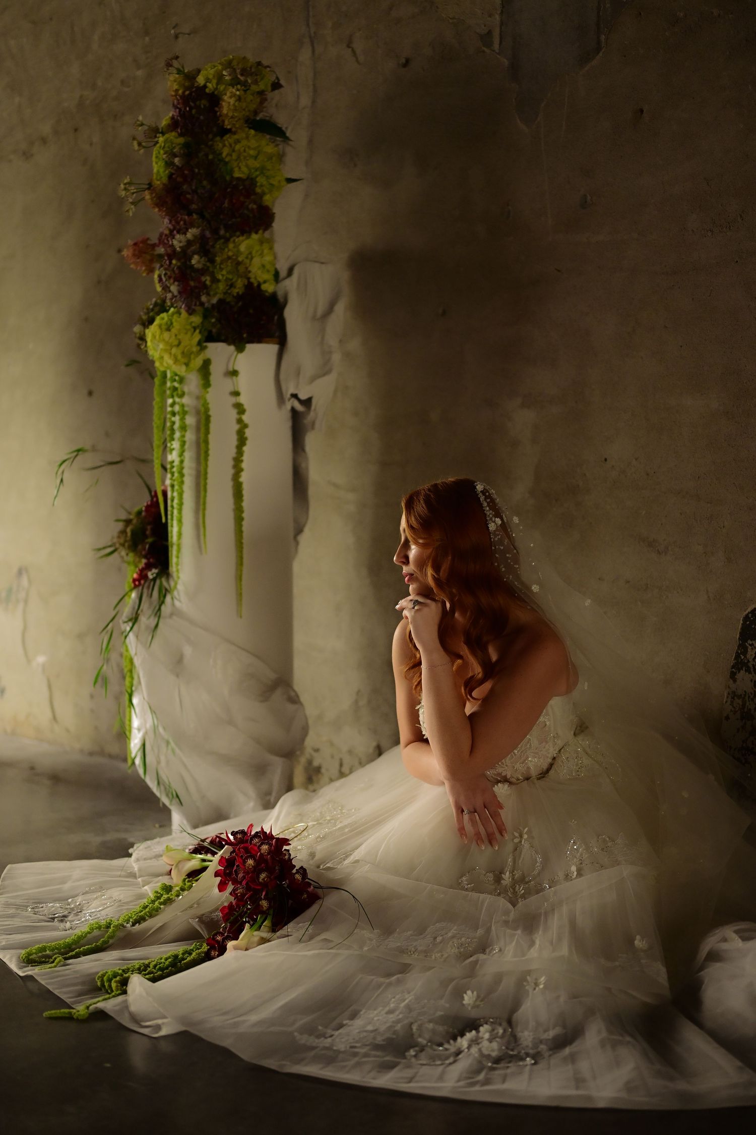 Classic architectural wedding photo in stone colonnade with dramatic lighting.
